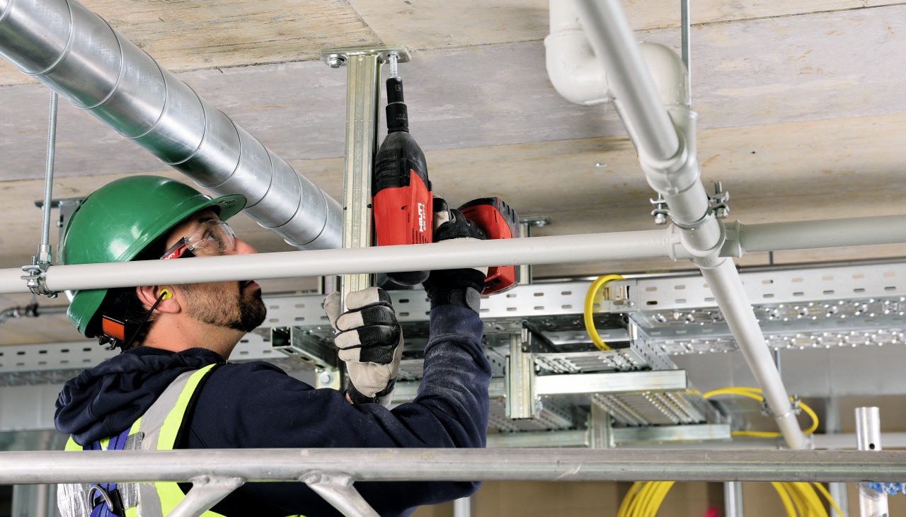 Un operario fija en un techo de hormigón con un atornillador Hilti