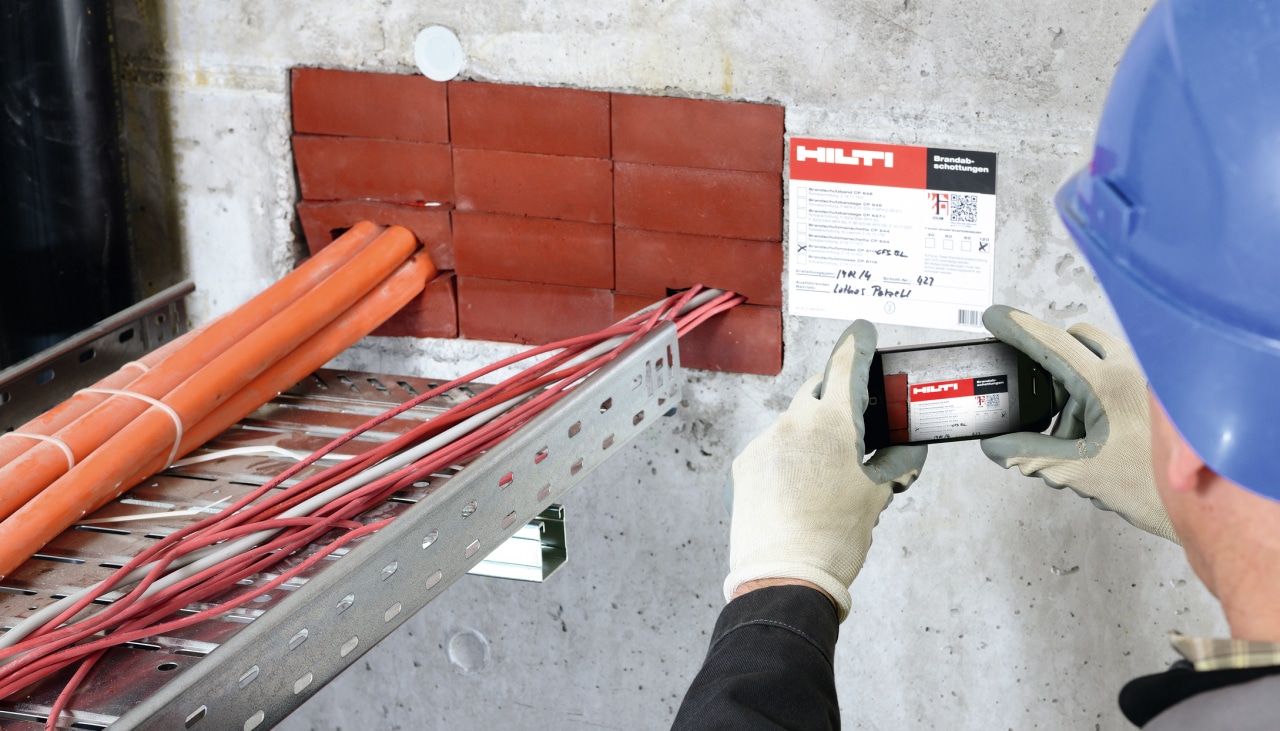 ChatGPT said: Un operario fotografía la documentación de protección contra incendios de Hilti con su teléfono