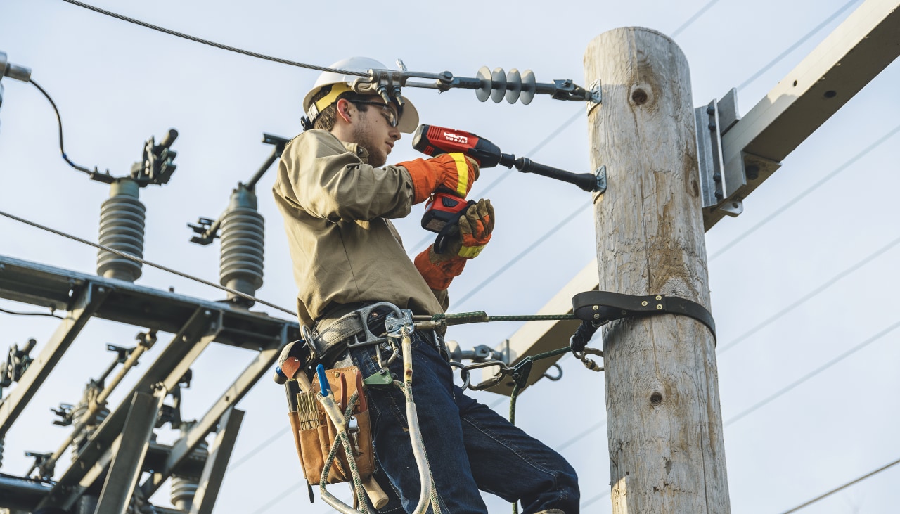 Fijación de cables en un poste eléctrico con una llave de impacto inalámbrica.