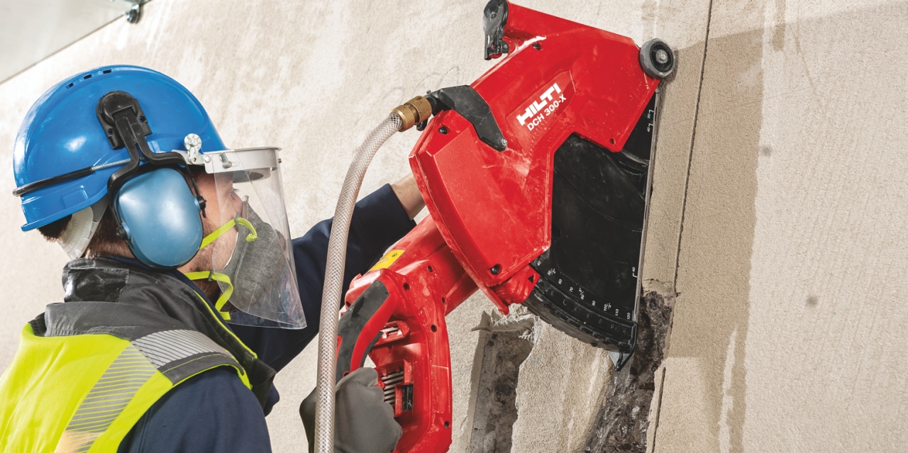Trabajador de la construcción cortando hormigón con una DCH 300-X que está equipada con un protector de disco para proteger a los trabajadores de los discos rotos