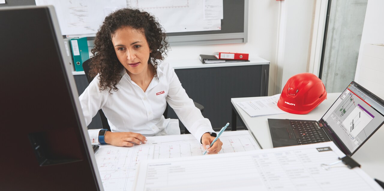 Ingeniero de Hilti in situ con un cliente con planos en primer plano